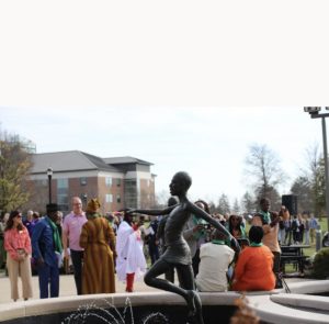 Crowd standing behind a statue